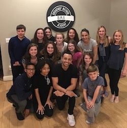 Noah Ricketts (centro arrodillado) enseñando teatro musical a los estudiantes de Broadway Method Academy en Connecticut