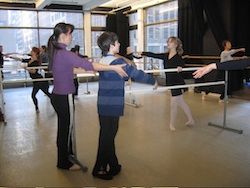 Юка Кавазу поправя млад танцьор в класа си по балет